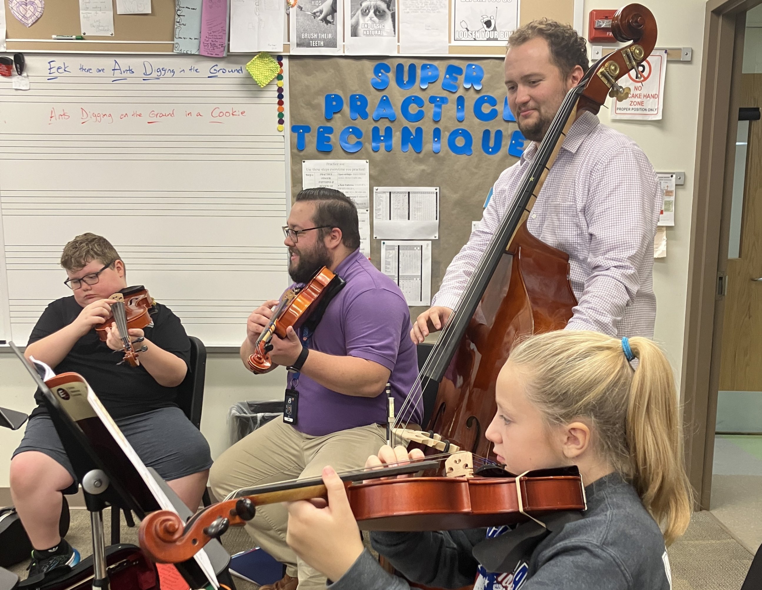 Mr. King and Mr. Craine playing instruments alongside students during a viola lesson.